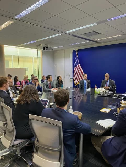Deputy Secretary Verma and officials meet at a conference table with an American flag behind them.