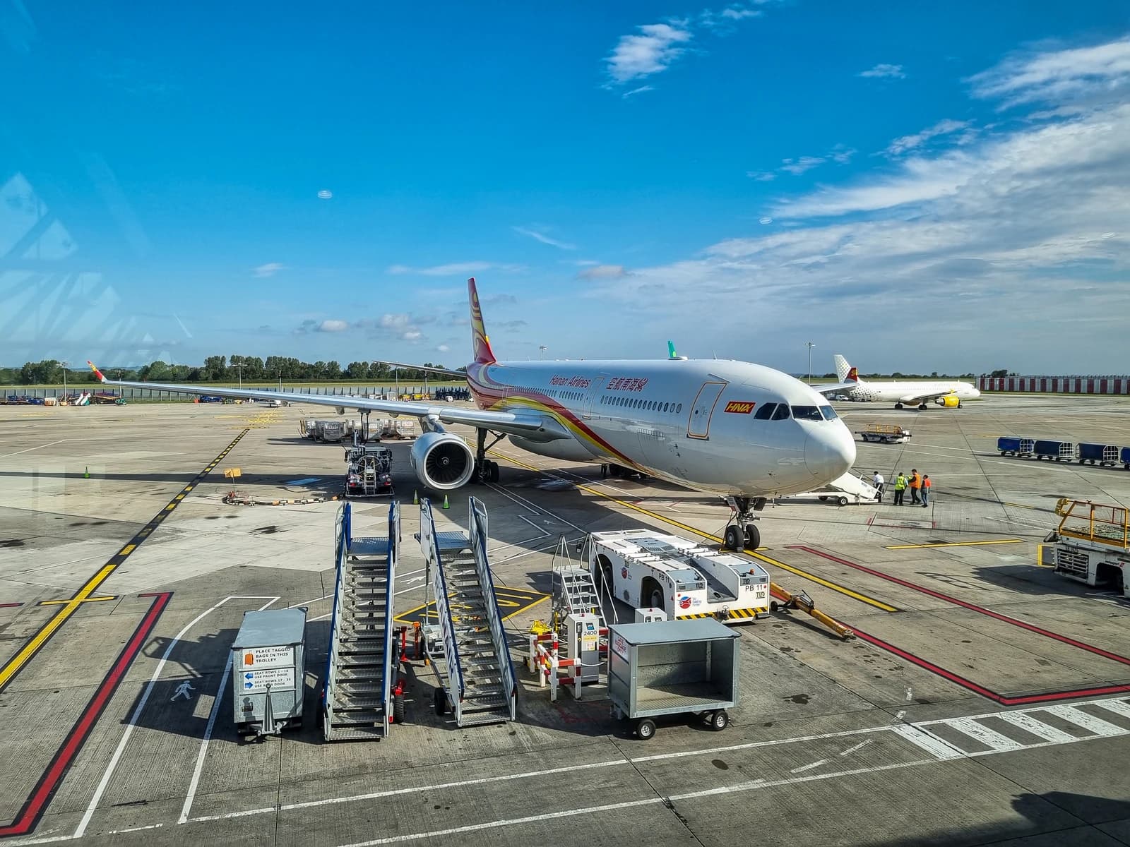 An Airbus A330-343 aircraft of Hainan Airlines parked at an airport gate.