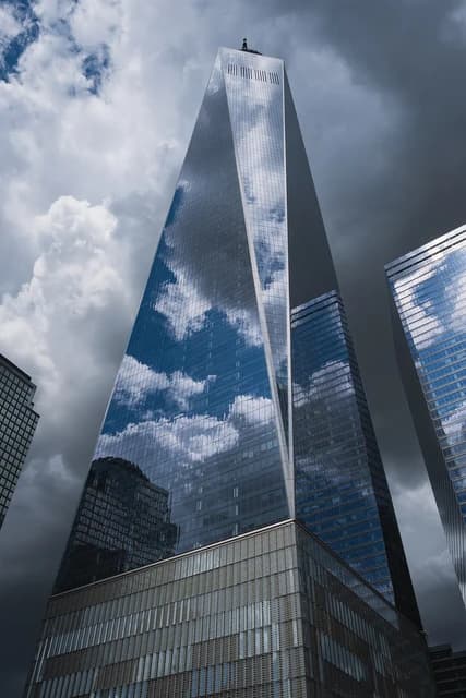 One World Trade Center skyscraper with clouds reflected in its glass facade.