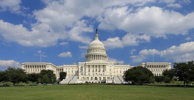 The United States Capitol Building, seen from the west, under a blue sky.