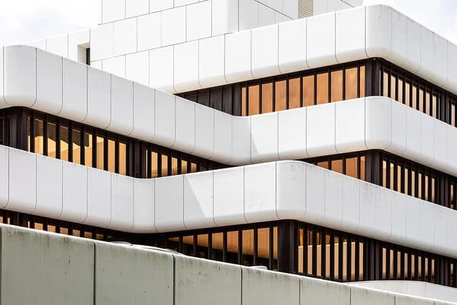 Modern multi-story building in Münster with white exterior and dark rectangular windows.