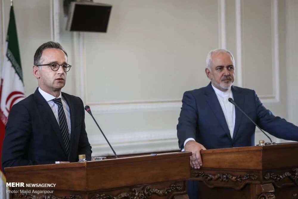 Heiko Maas and Mohammad Javad Zarif standing behind podiums during a press conference.