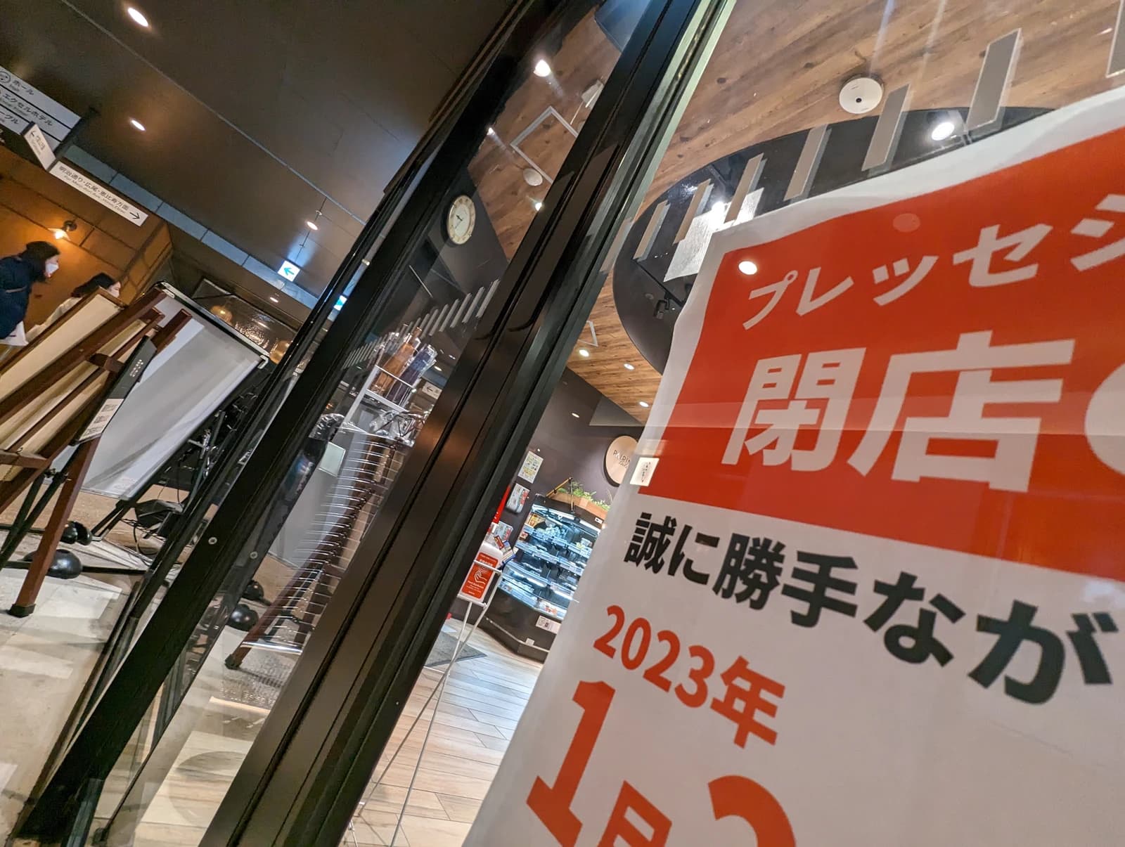 A red and white sign in Japanese announcing the closing of a business.