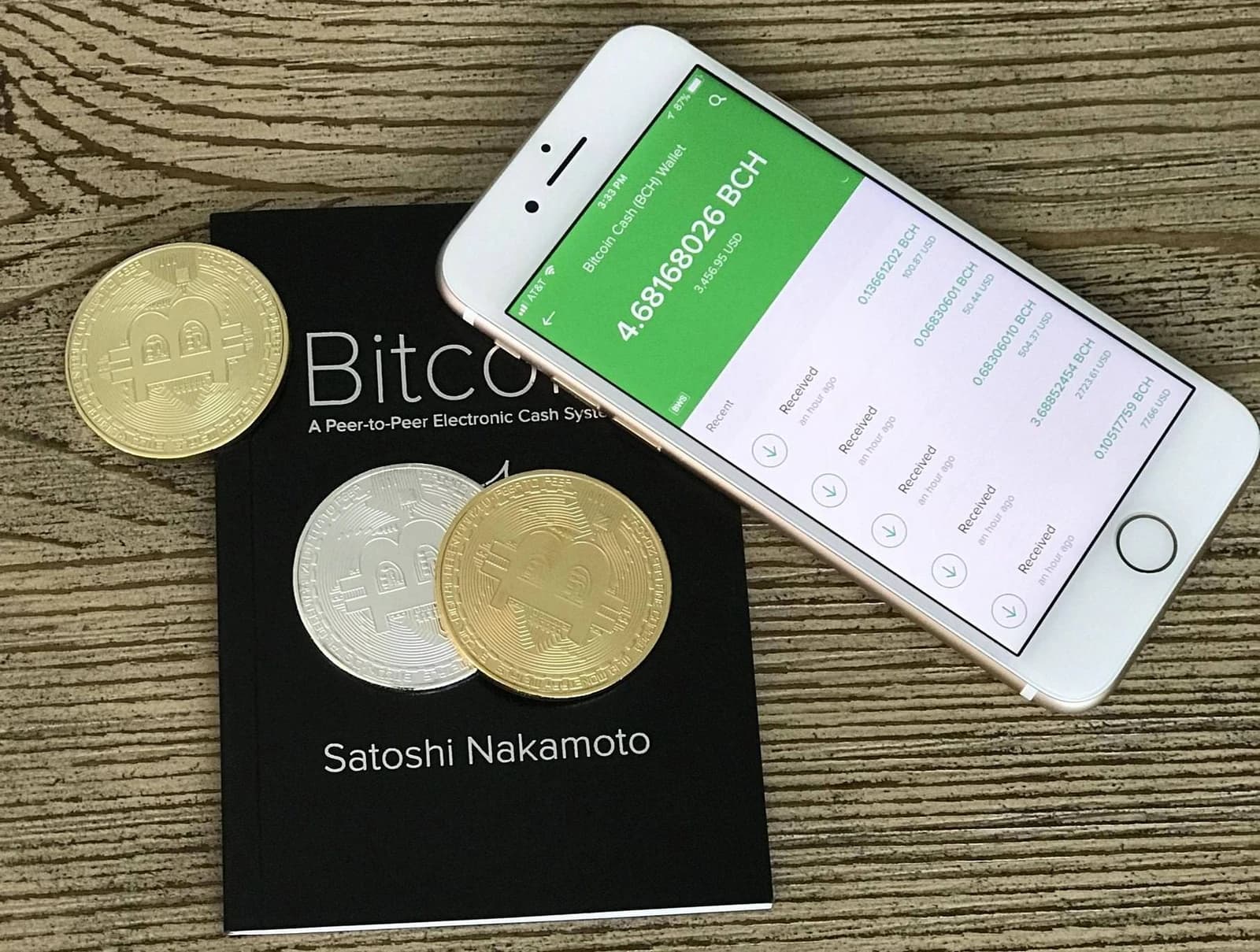 Bitcoin Cash wallet interface on a smartphone with physical Bitcoin tokens and whitepaper.