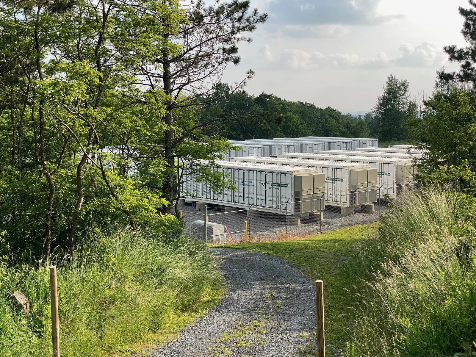 Invenergy Beech Ridge Energy Storage System with white battery containers, surrounded by trees.