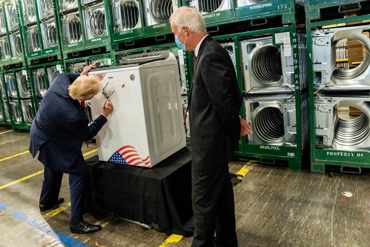 Donald Trump, President of the United States, signs a washing machine at a manufacturing plant.
