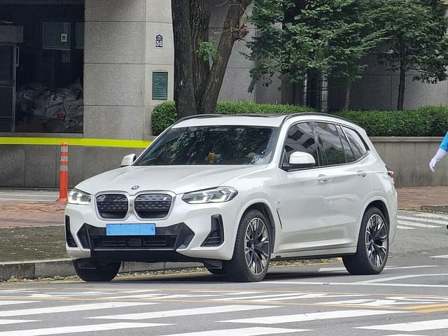 White BMW G08 LCI iX3 M Sport in Mineral White Metallic parked on a city street.