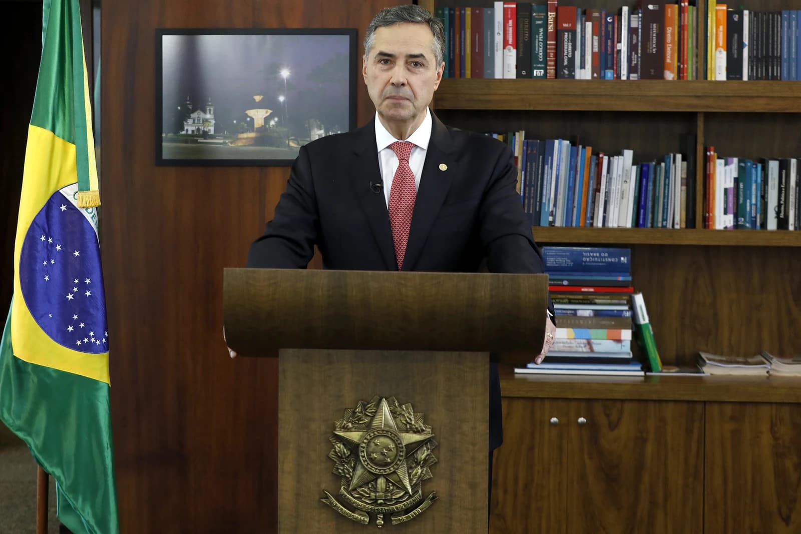 Minister Roberto Barroso standing at a podium speaking to the public.