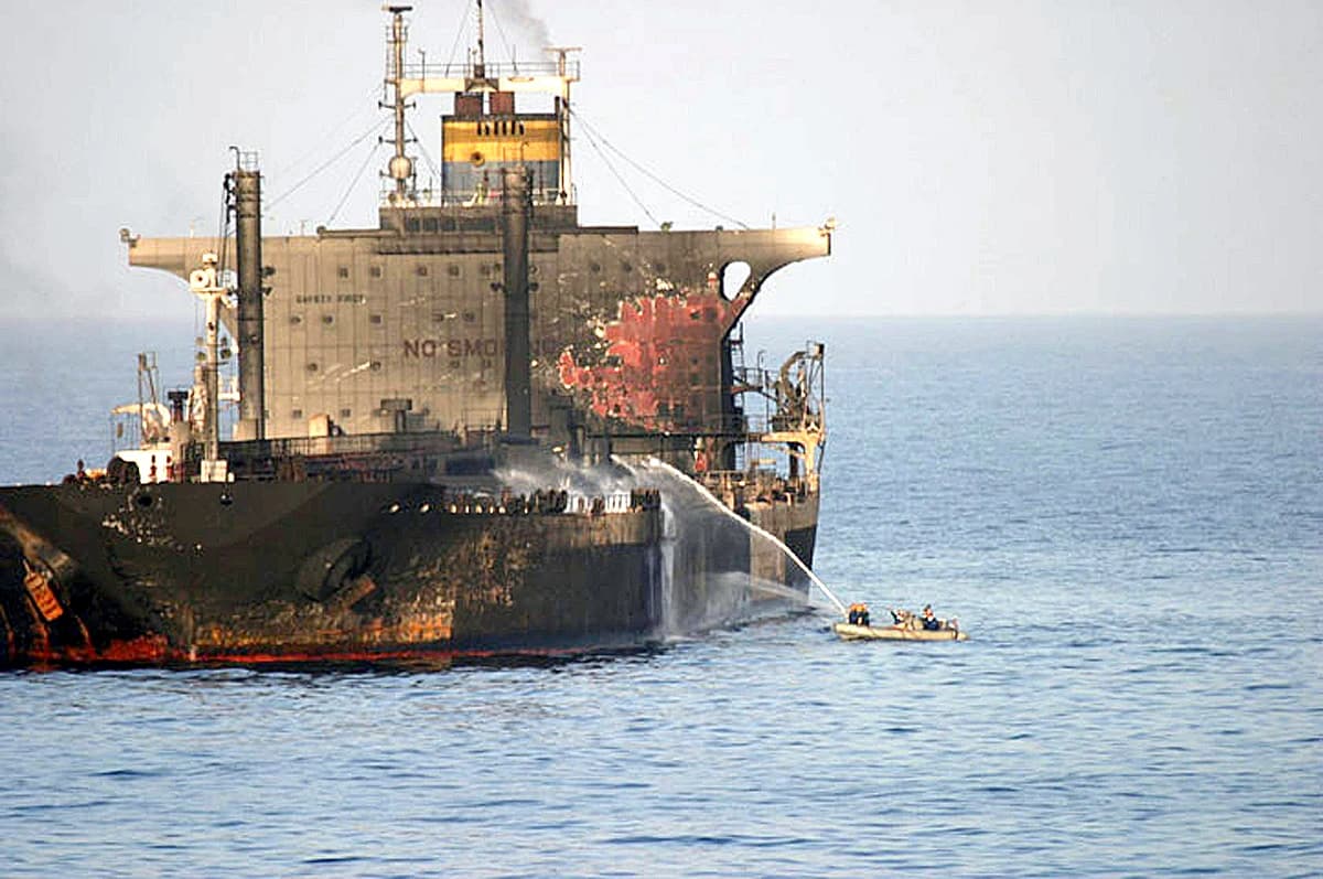 MV EVERTON, an oil tanker, burning at sea with firefighting efforts from a small boat.