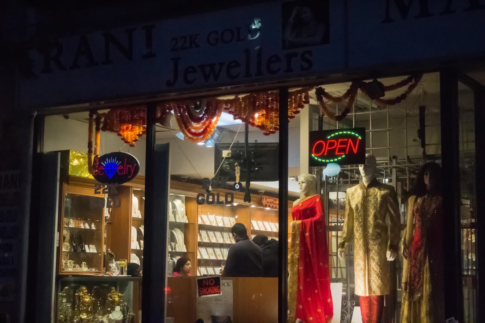 Jewellery store storefront with '22K Gold Jewellers' sign and an 'Open' neon sign.