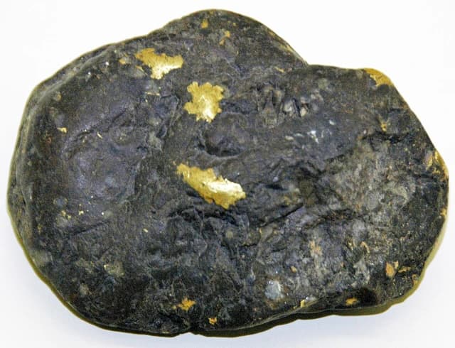 Native gold embedded within a dark rock formation from Silver Bow Creek, Montana.
