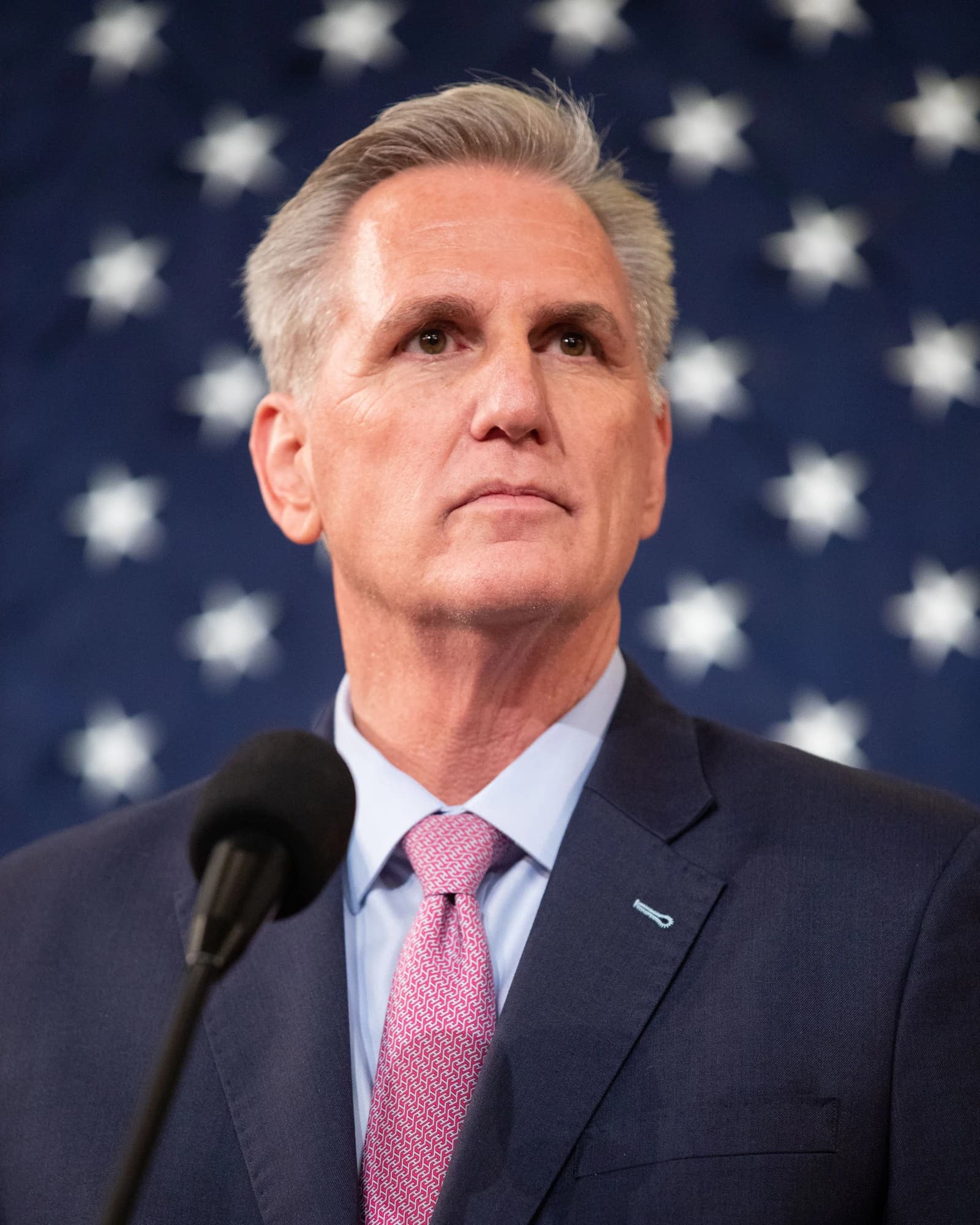 Kevin McCarthy, former Speaker of the House, stands at a podium in front of an American flag.
