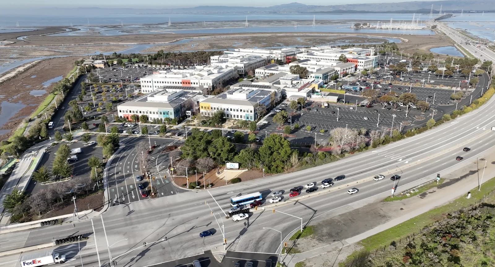 Aerial view of Meta Platforms headquarters campus next to a highway and body of water.