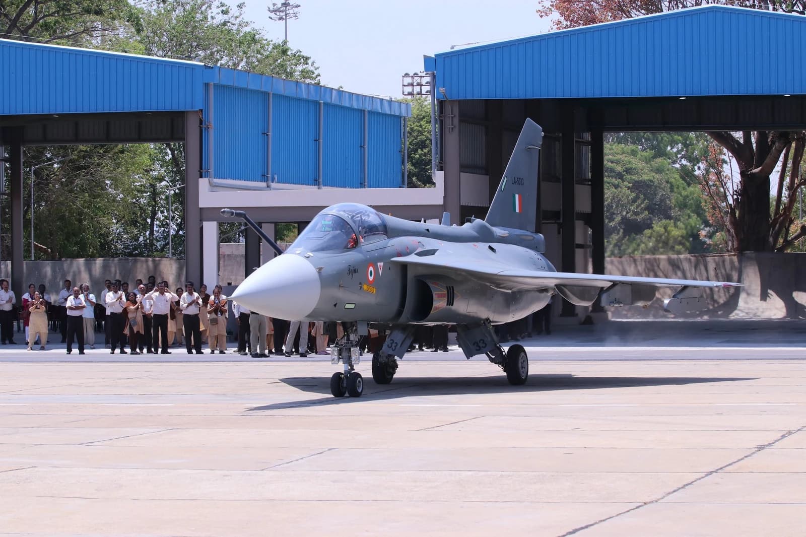Tejas Mark 1A light combat aircraft parked on an airfield with people watching.