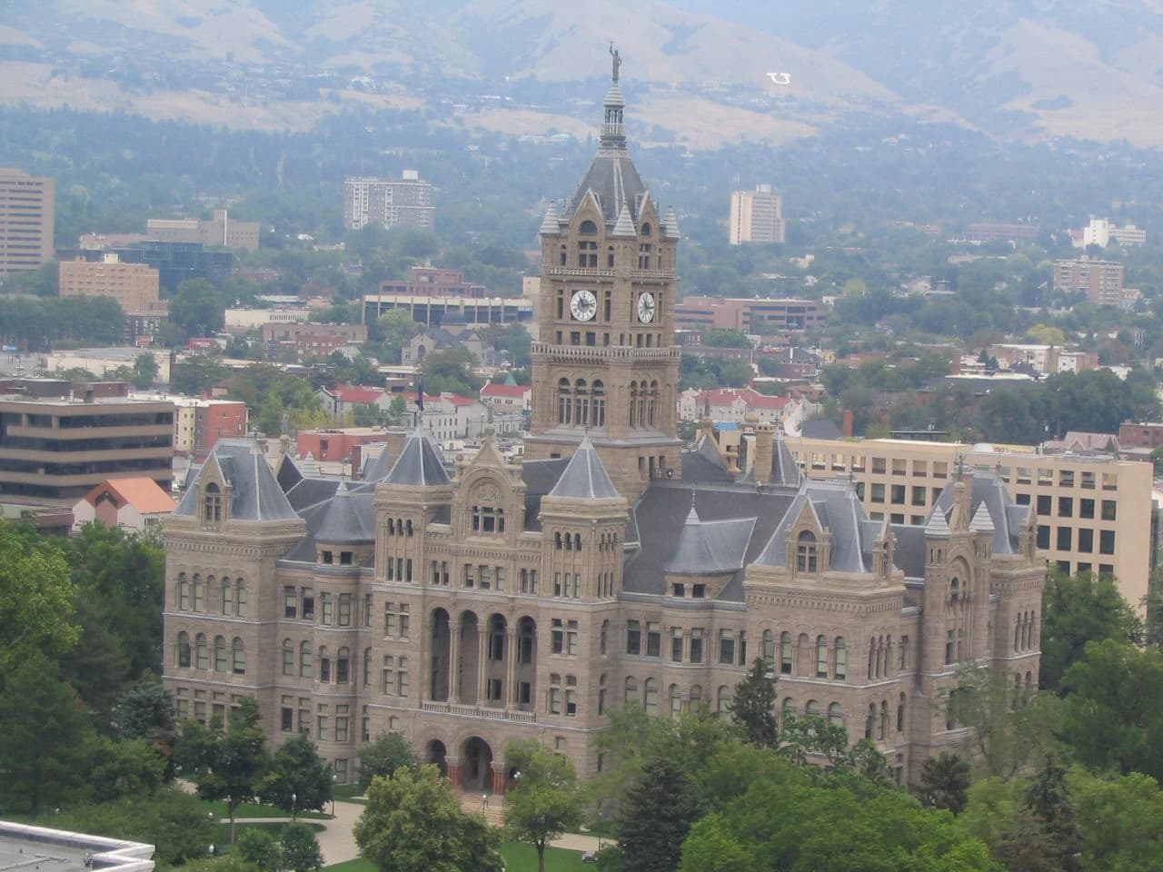 Salt Lake City and County Building stands prominently amidst other buildings and distant mountains.