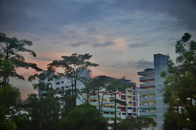 Public housing buildings with colorful facades against a cloudy, sunset sky in Singapore.