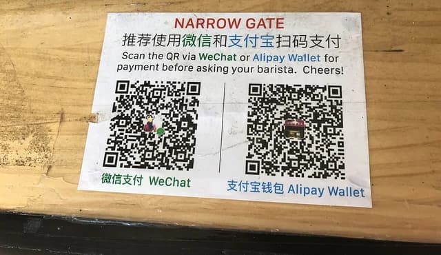 Two QR codes for mobile payment, one for WeChat and one for Alipay, displayed on a counter.