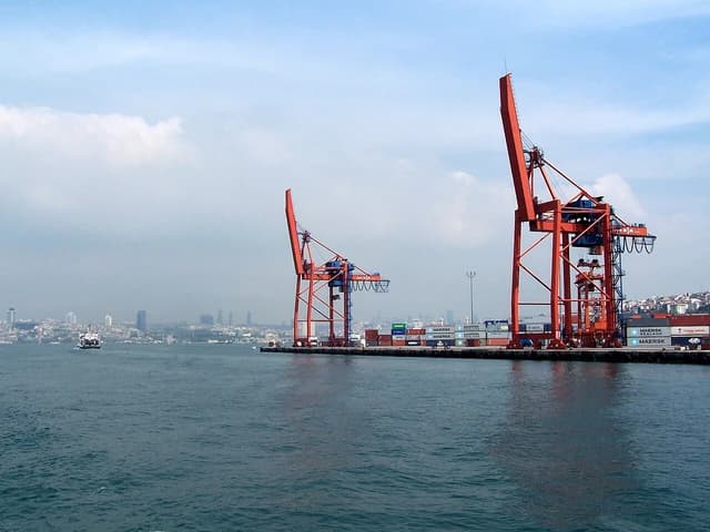 Port of Haydarpaşa, Turkey, with large red container cranes and shipping containers along the dock.