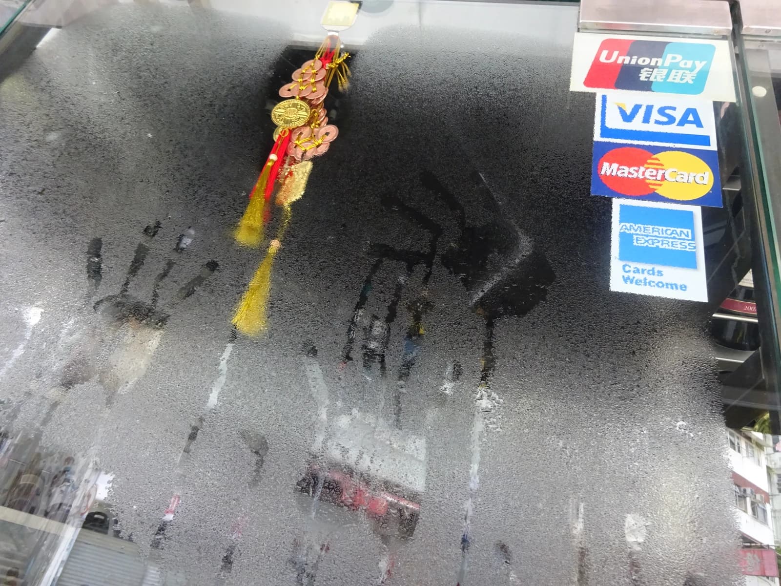 Credit card logos for UnionPay, VISA, MasterCard, and American Express on a condensation-covered shop window.