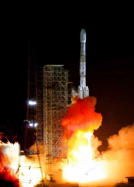 Chinese Long March 3B rocket launching from a pad at night.