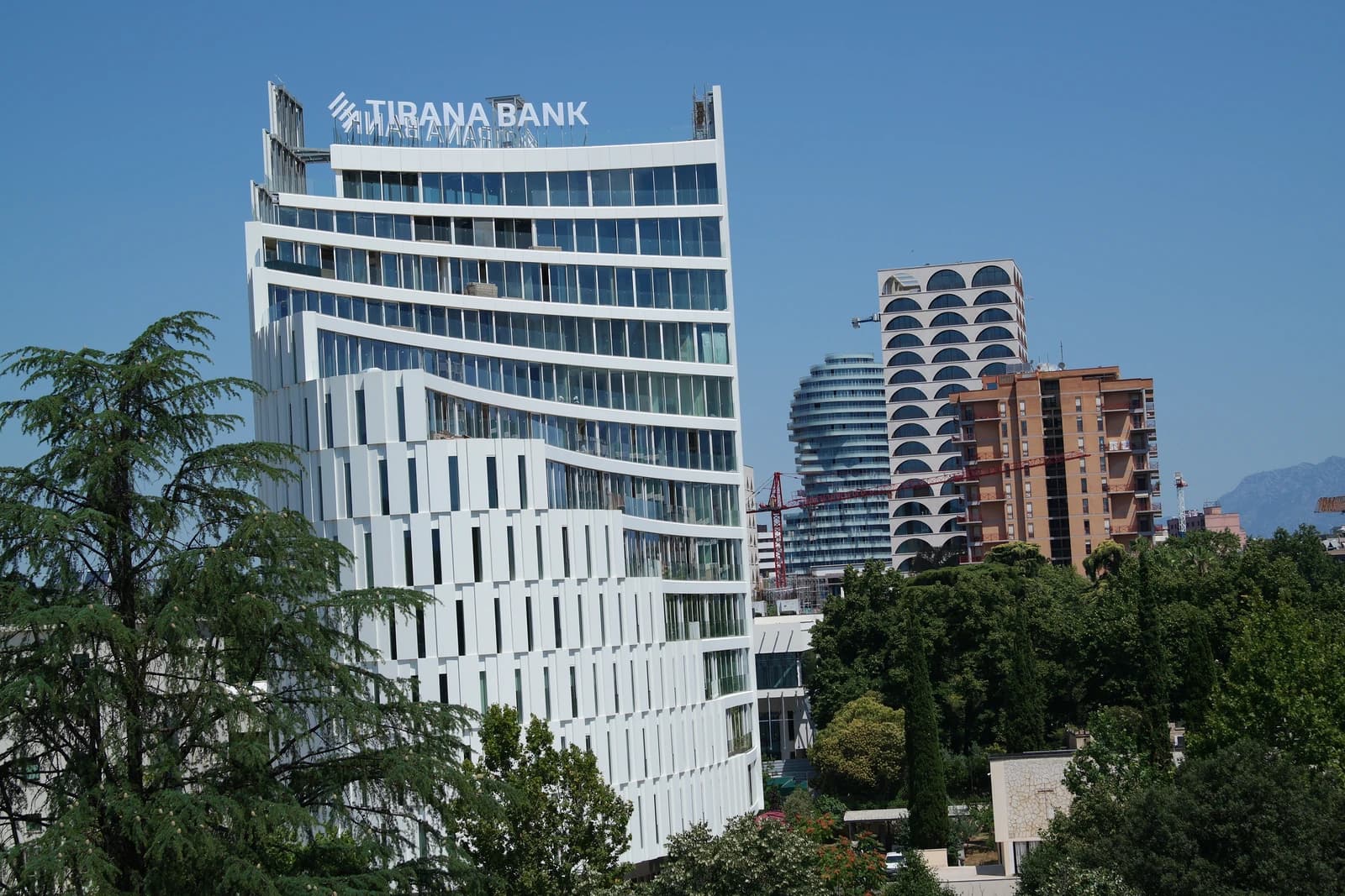 Modern high-rise building with 'Tirana Bank' logo visible on its top.