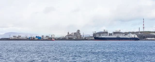 An LNG tanker docked at a liquefied gas terminal on a cloudy day.