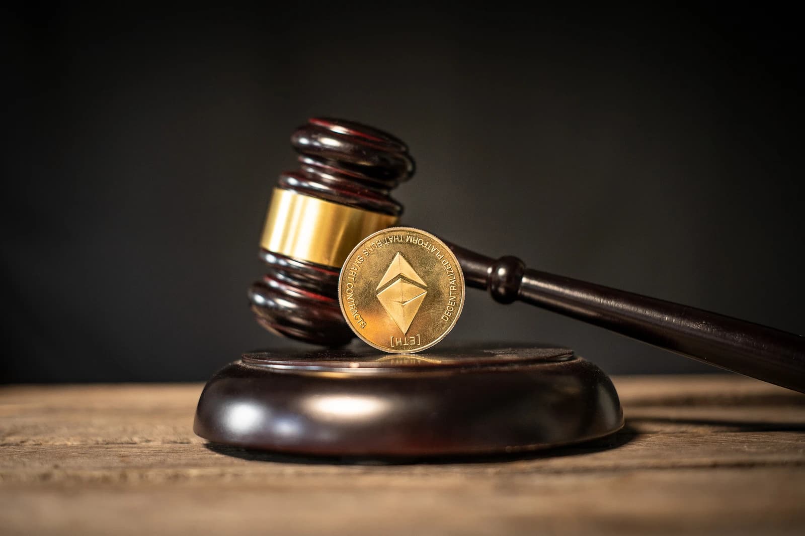 An Ethereum cryptocurrency coin stands upright on a judge's gavel.
