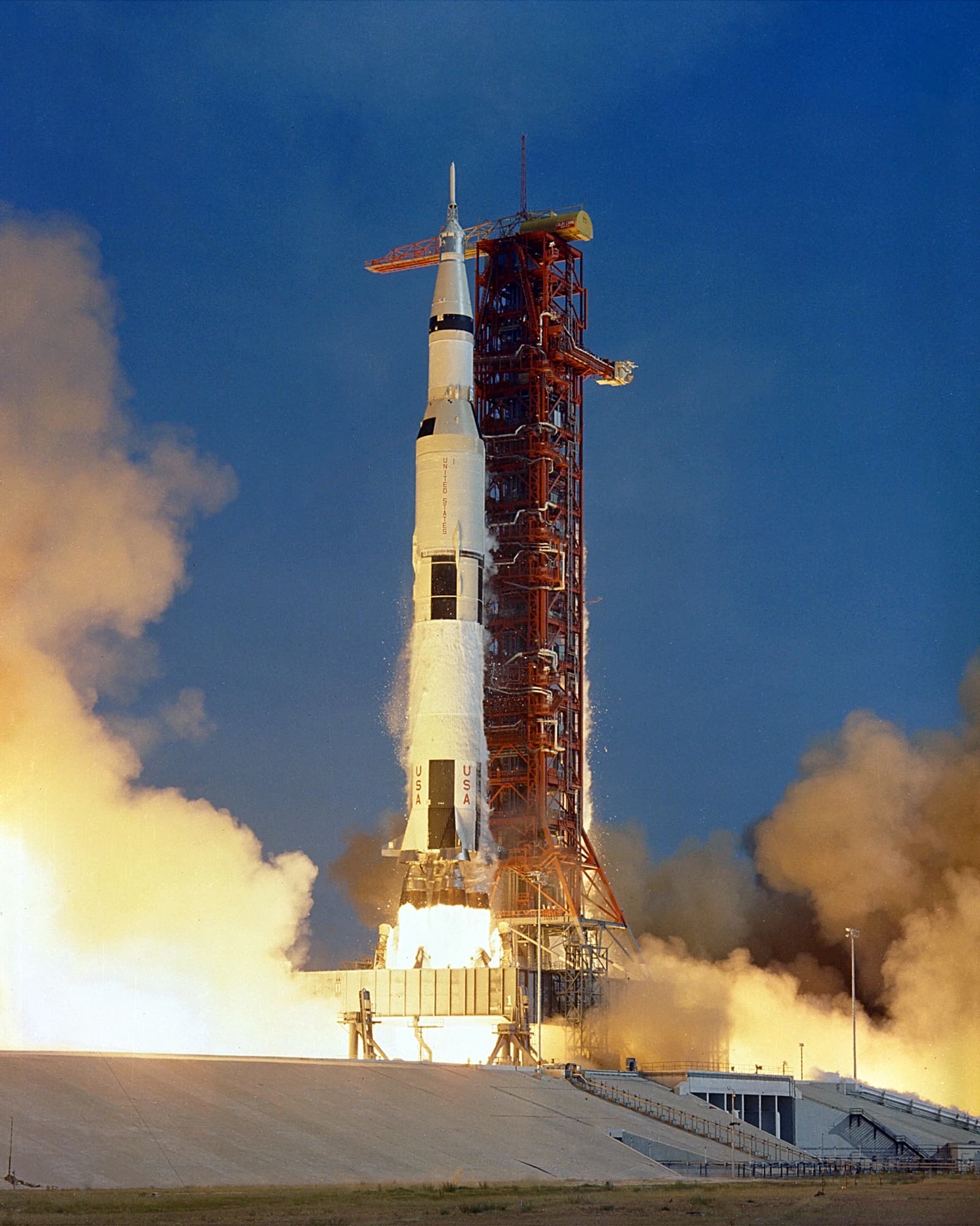 Apollo 11 Saturn V rocket launching from its launchpad, surrounded by smoke and fire.