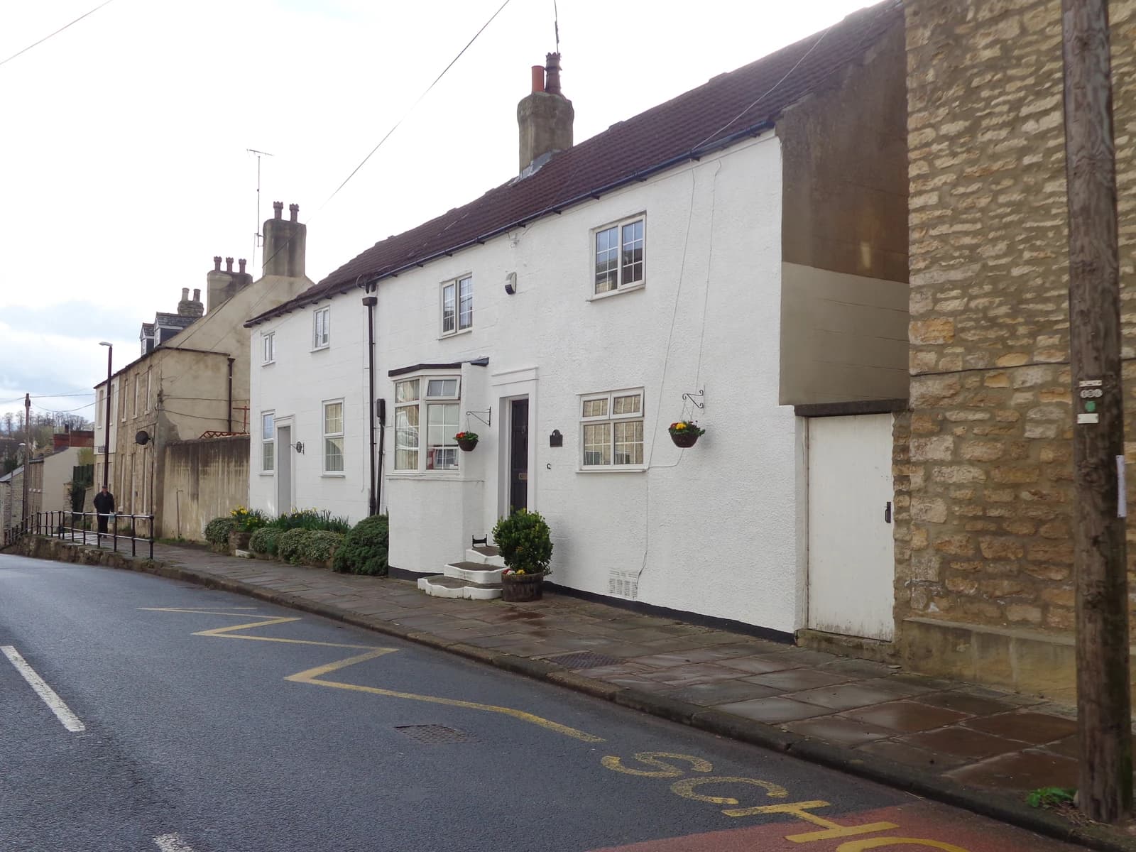 Rose and Crown Cottage, a white house with a brown roof on a street.