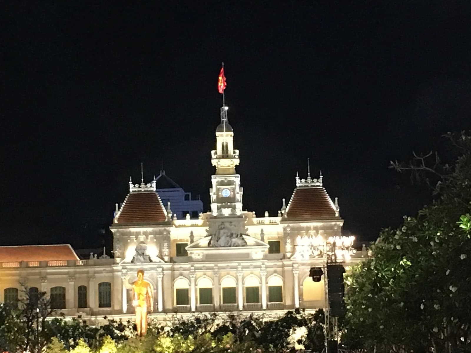 People's Committee Building of Ho Chi Minh City at night with flag atop.