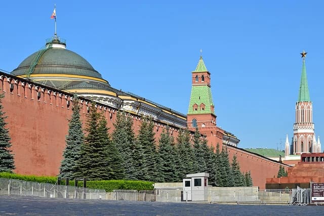 The red brick Kremlin wall and a tower with a green roof on Red Square in Moscow.