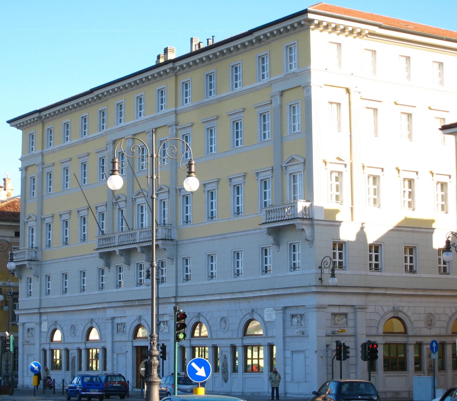 Fincantieri headquarters building with street lamp and cars in foreground.