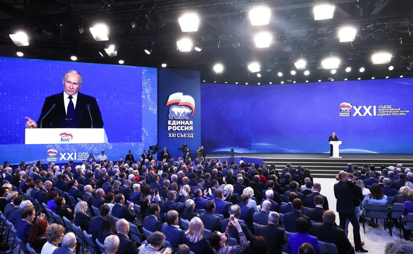 Vladimir Putin, President of Russia, speaking from a podium at a large political conference.