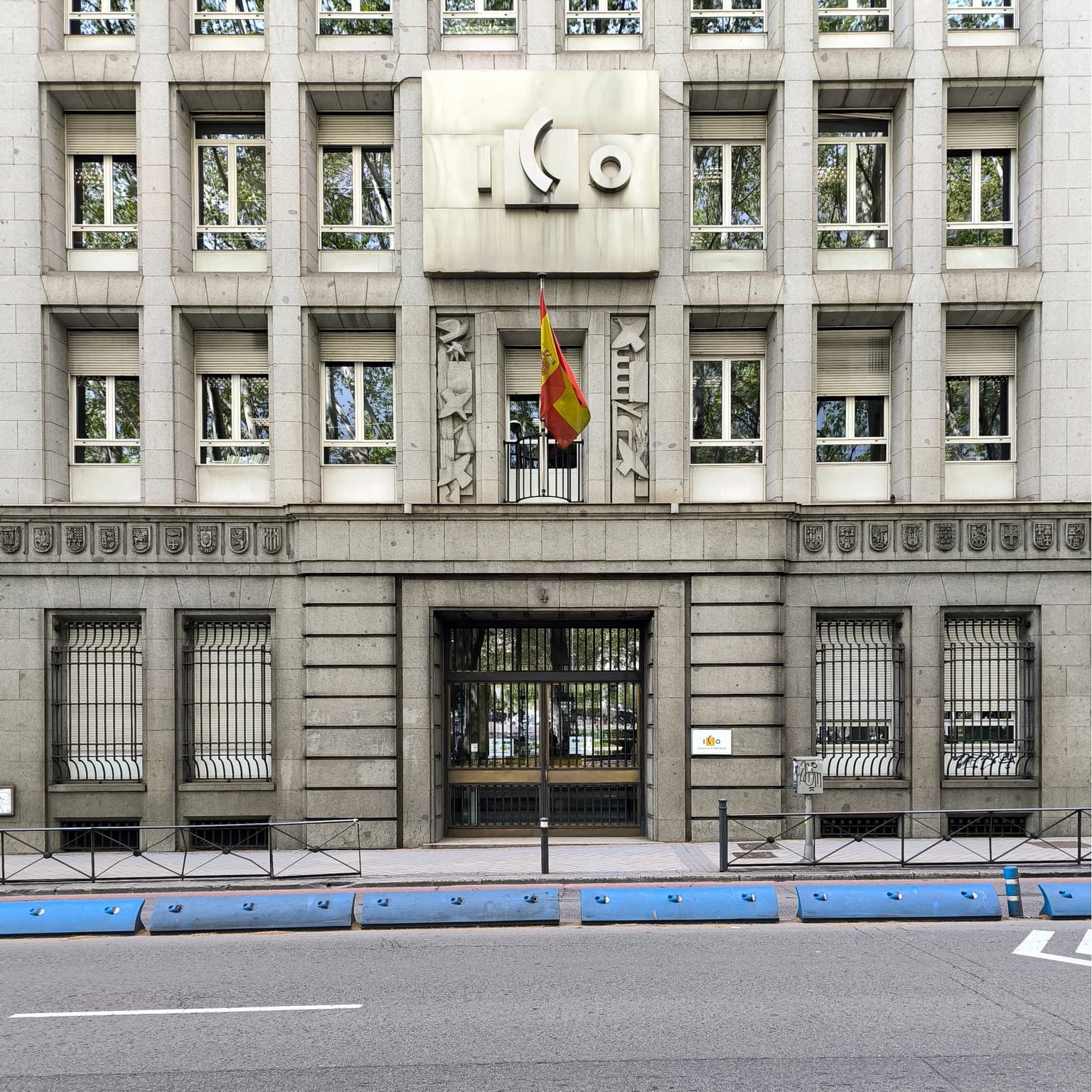 Facade of the ICO building with a Spanish flag hanging from a balcony.