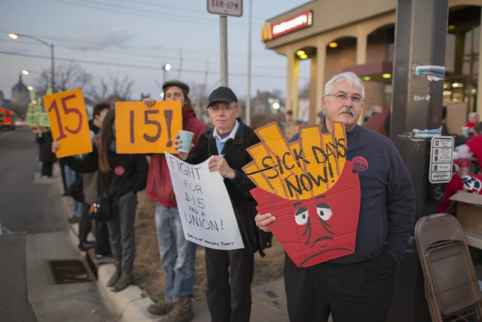 Fast food workers hold signs protesting for higher minimum wage and better benefits.