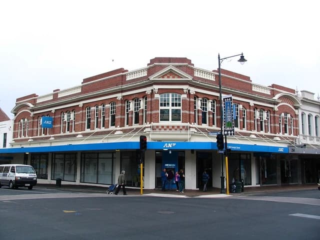 ANZ bank building on a street corner with people and a van nearby.