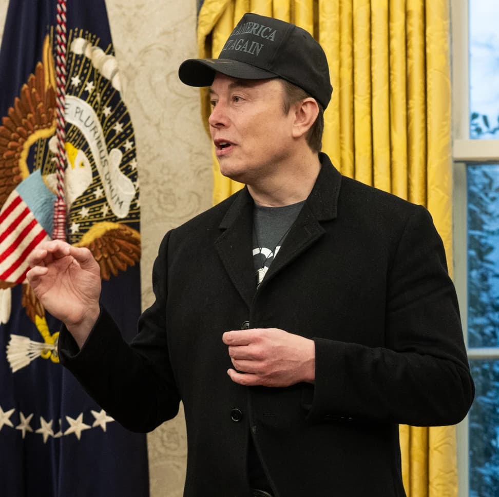 Elon Musk speaks in the Oval Office with the Presidential Seal in the background.