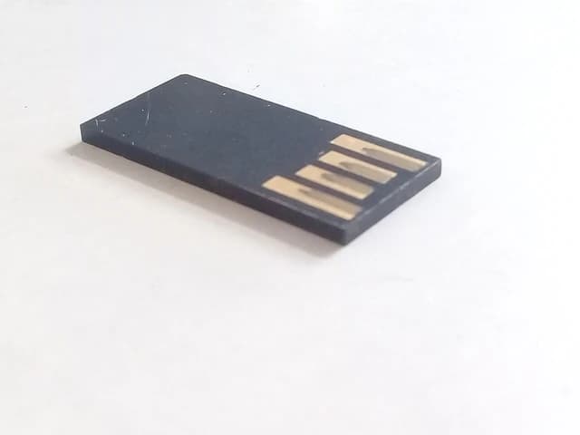Small black USB flash drive chip with gold-colored electrical contacts.