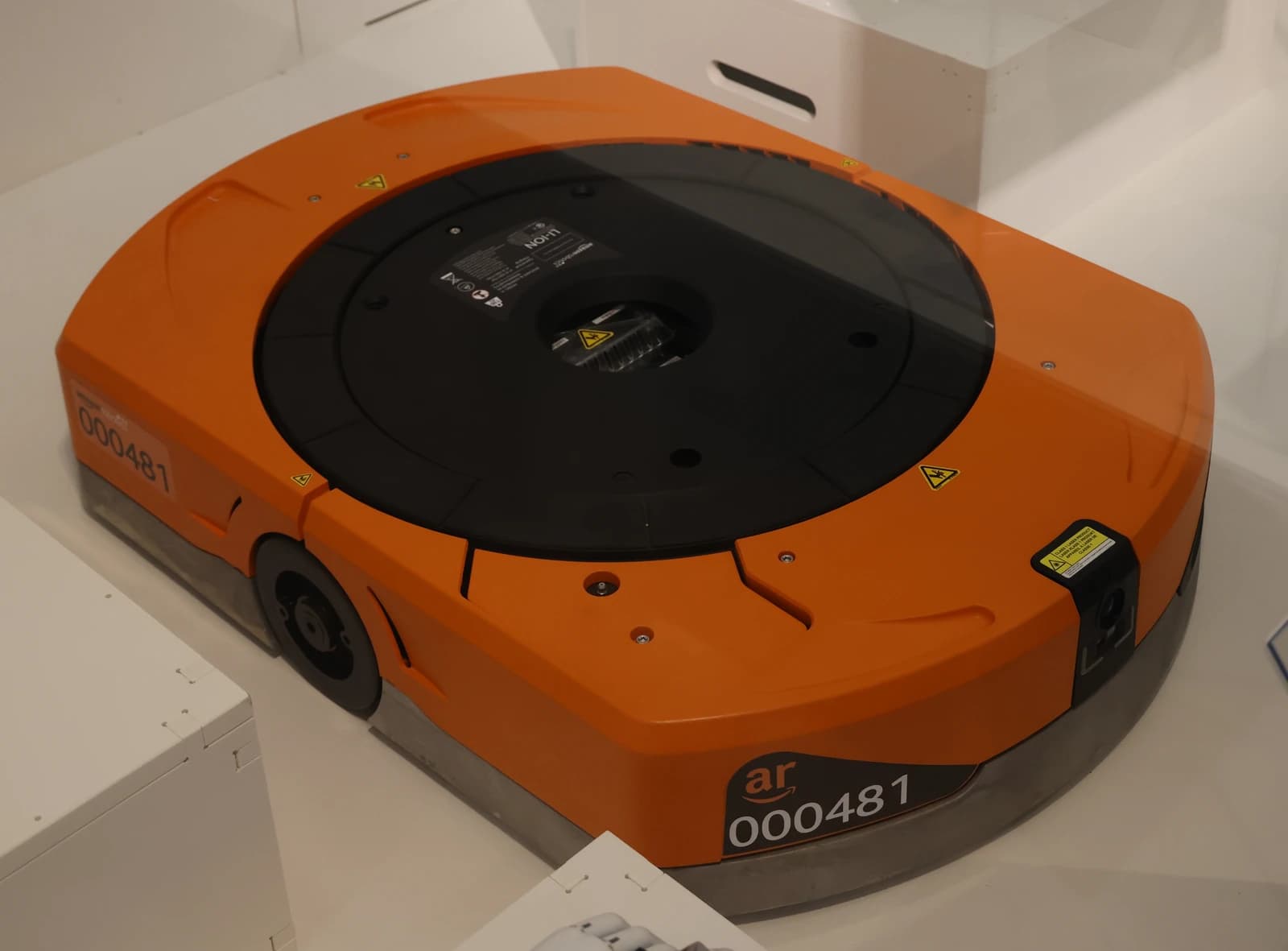 An orange and black Amazon warehouse robot with wheels on display.