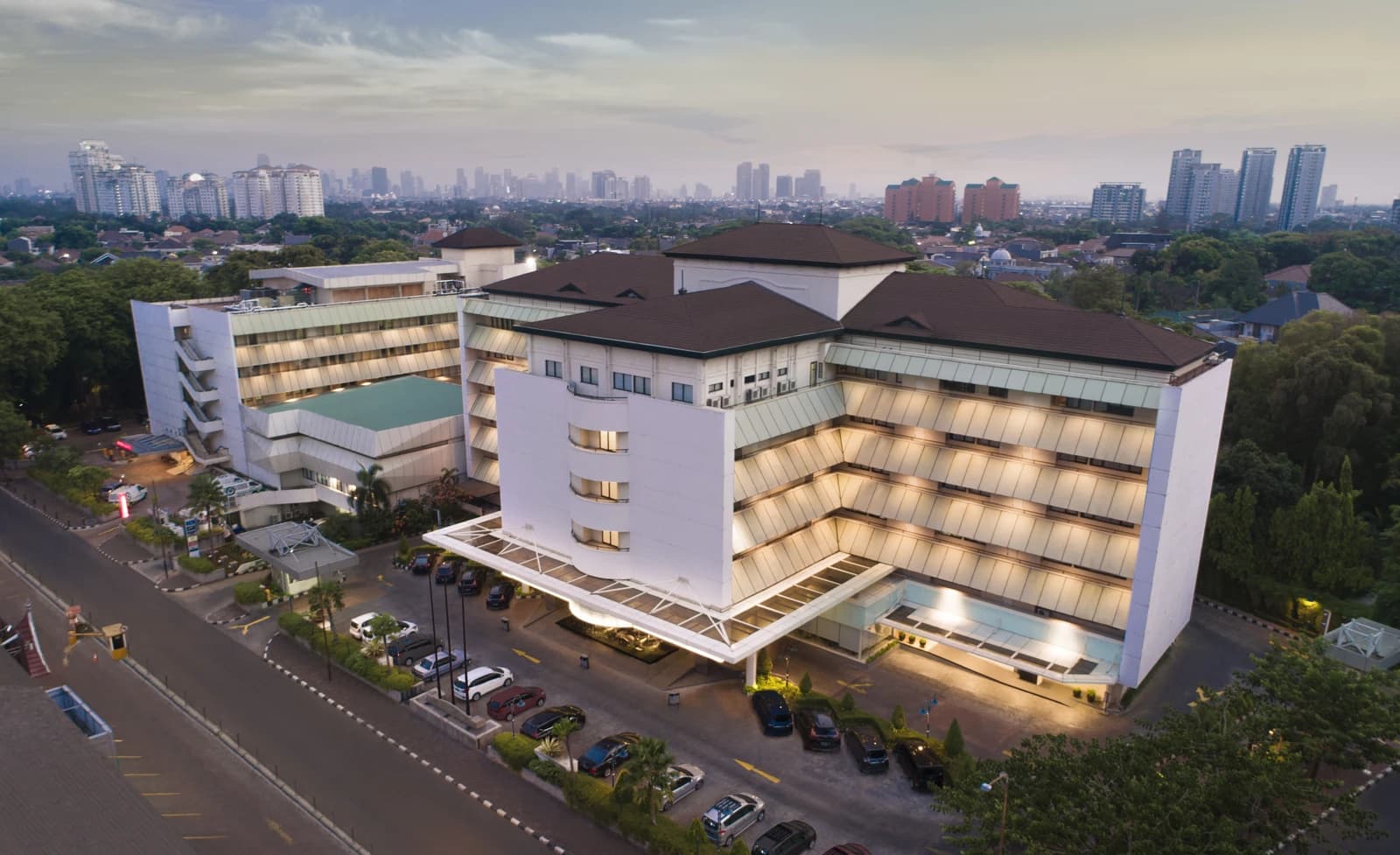 Aerial view of RS Pondok Indah hospital building with cars parked outside.
