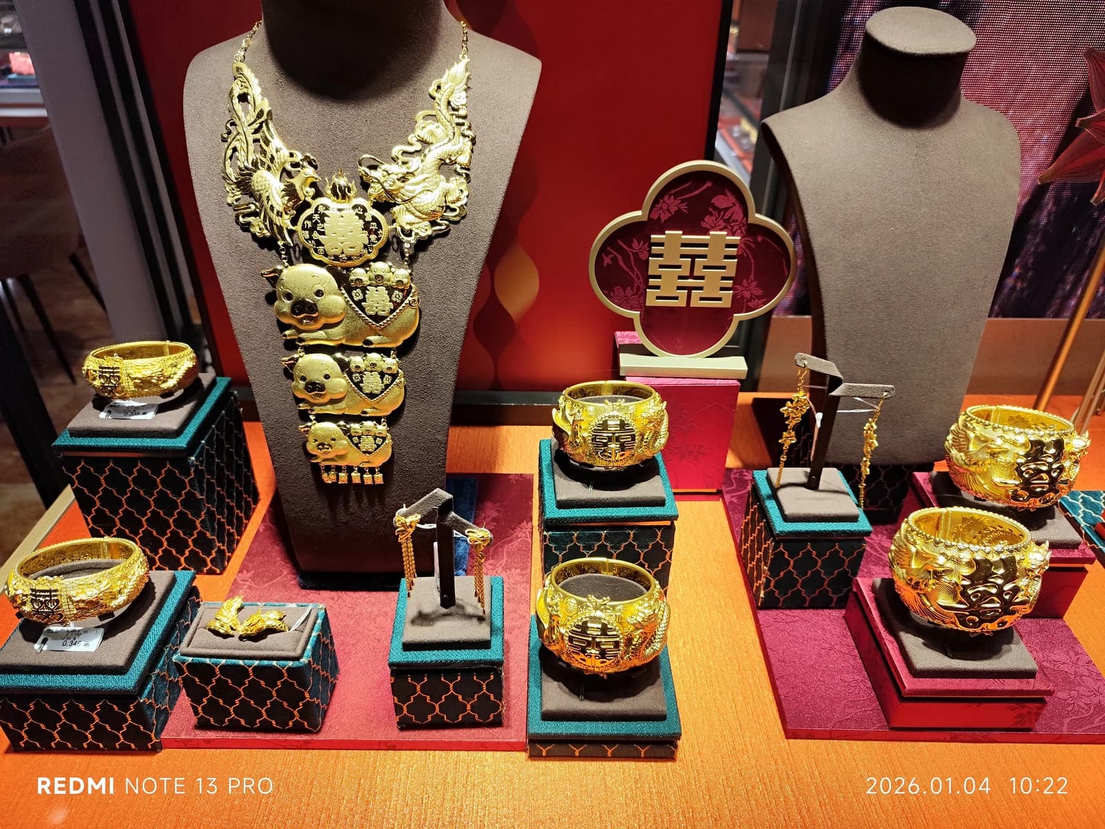 Intricately designed gold jewelry, including necklaces and bracelets, displayed in a shop.