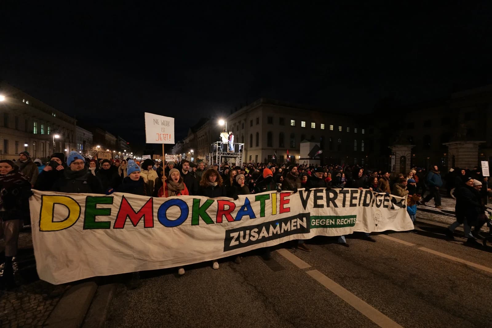 People demonstrating with a banner in German that translates to "Defend Democracy Together Against the Right."