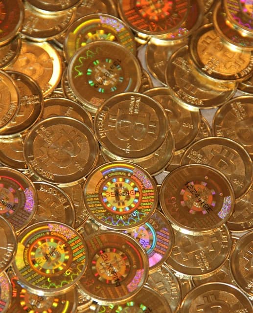 Close-up of physical Bitcoin coins with a holographic security label on each coin.