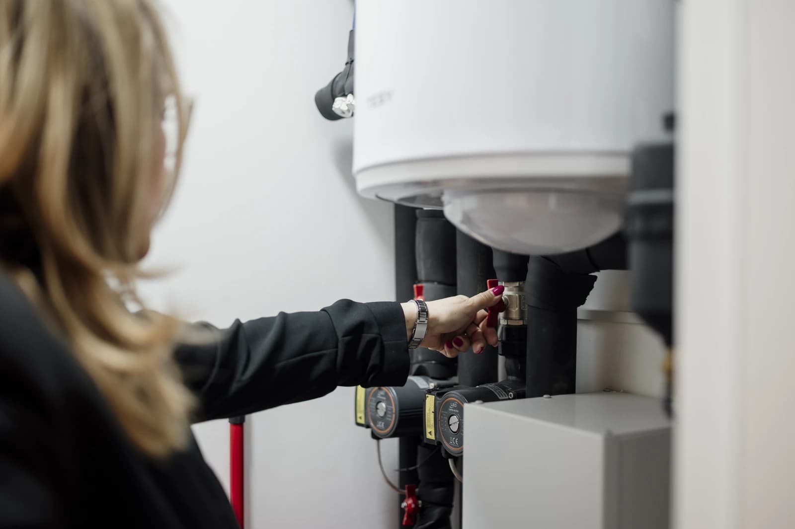 Businesswoman operates valve in a utility room to manage plumbing system for heat pump in a residential building.