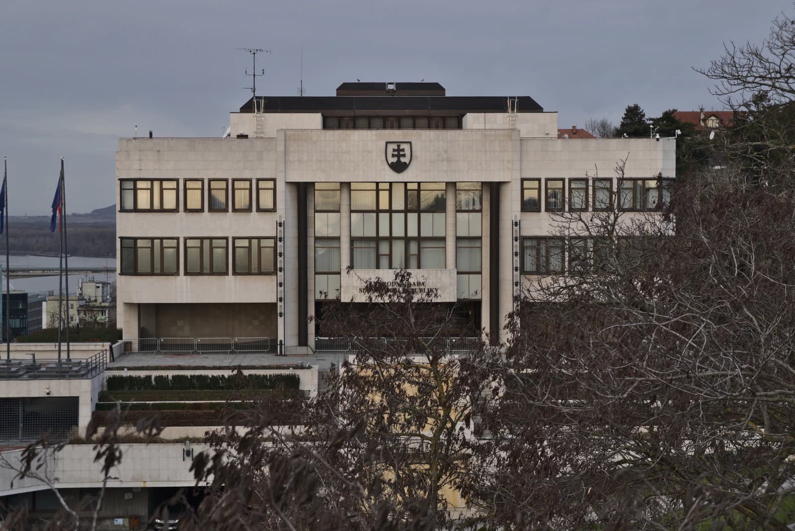 Main building of the National Council of Slovakia in Bratislava under a cloudy sky.