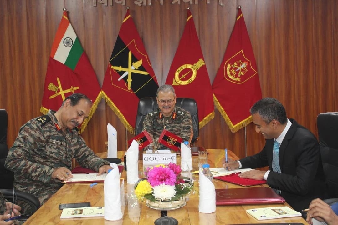 Dr. Sudhir Krishnaswamy and Major General V. M. Chandran signing a Memorandum of Understanding at a table.
