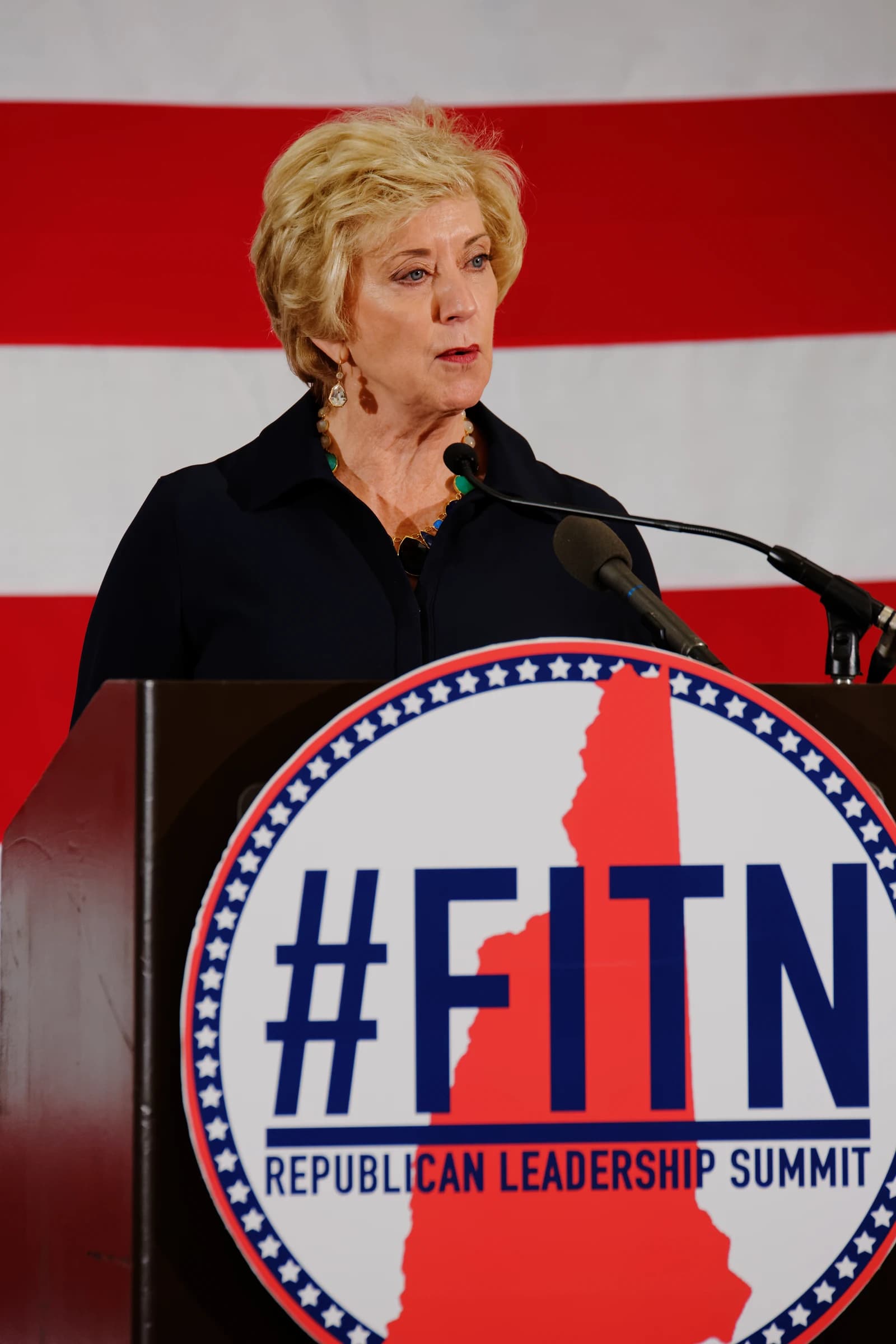 Linda McMahon, former WWE CEO, speaking at a podium in Nashua, New Hampshire.