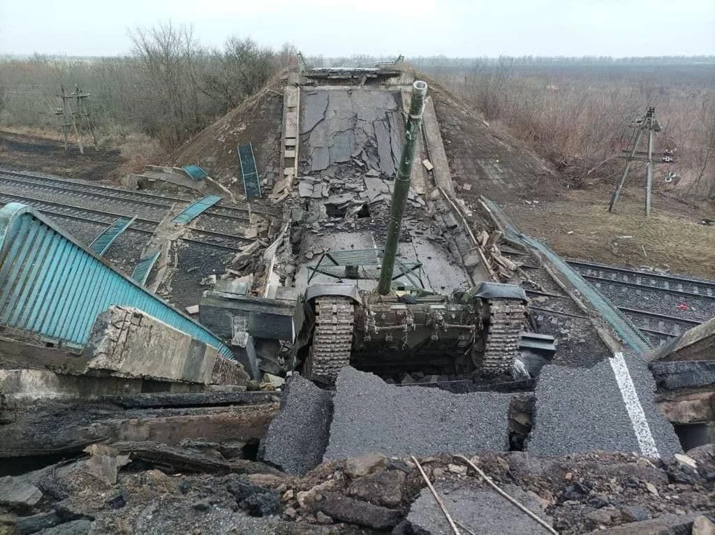 Russian tank trapped in a demolished bridge over railway tracks.
