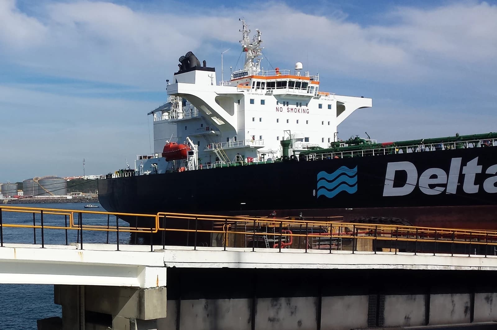 Large oil tanker ship, with 'Delta' written on its hull, docked at a port.