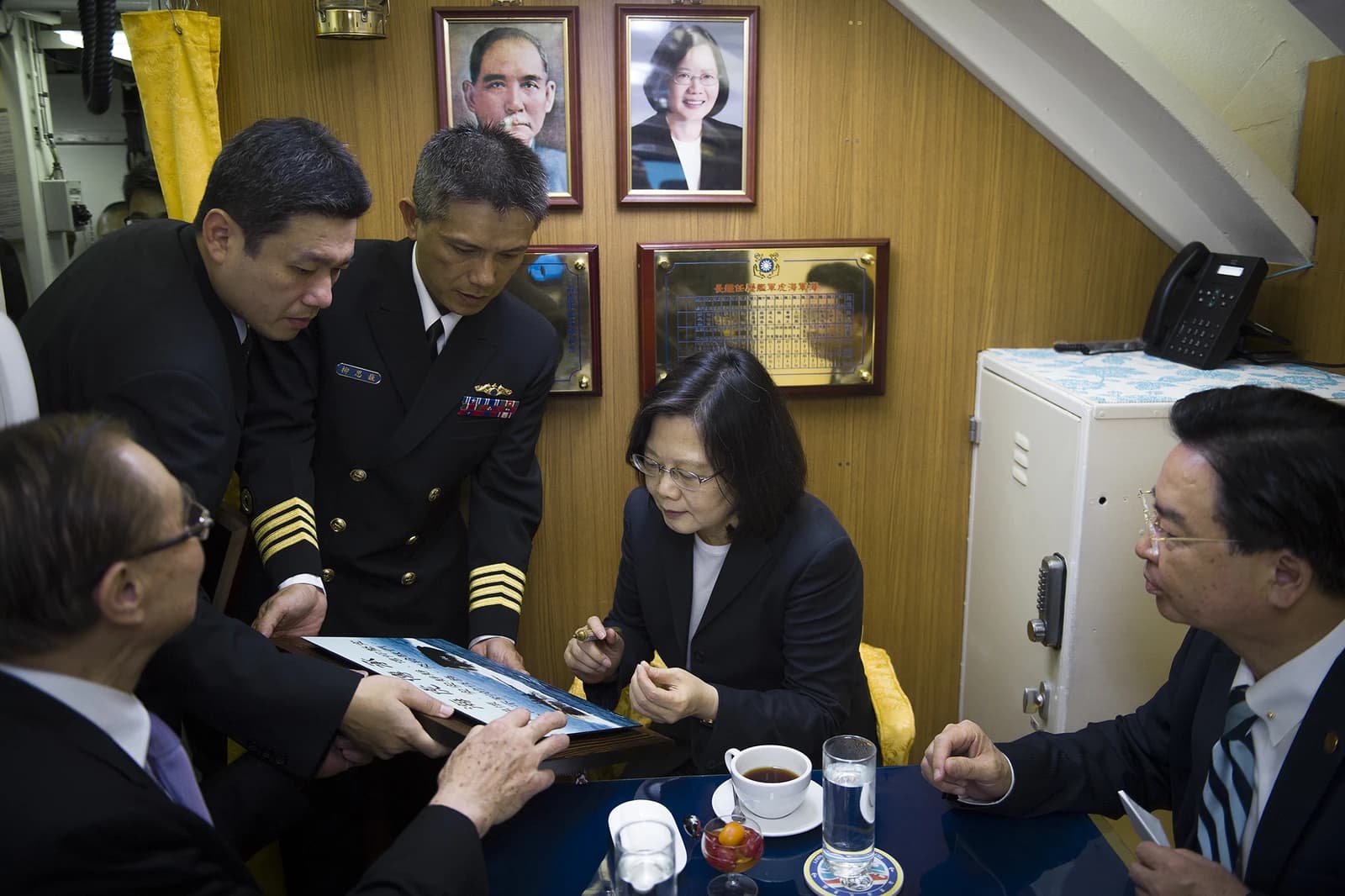 Taiwanese President Tsai Ing-wen signing a document with naval officers on a ship.
